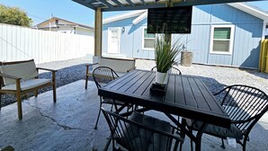 Un patio al aire libre con una mesa y sillas de madera, un ventilador de techo y una planta en maceta.