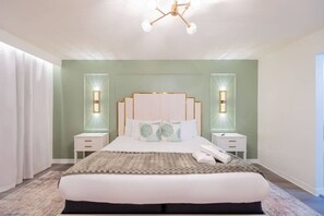 A modern bedroom with a large bed, two bedside tables, a chandelier, and wall sconces. - Cozy 4br House w/ EV Charger & Perfect Location! (Kissimmee)
