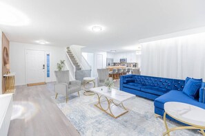 A modern living room with a blue sofa, grey armchairs, and a white coffee table. - Cozy 4br House w/ EV Charger & Perfect Location! (Kissimmee)