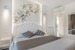 Una camera da letto con un letto grande, un condizionatore d'aria a parete e una porta che dà su un'altra stanza.