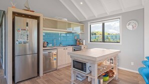 Una cocina moderna con horno integrado, microondas e isla de madera con espacio de almacenamiento.
