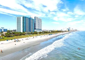 A beach with a row of high-rise buildings in the background.