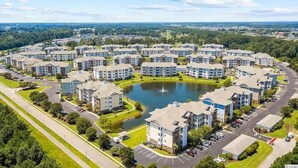 A residential complex with multiple apartment buildings, a central pond, and a surrounding green area.