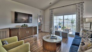A modern living room with a sofa, armchairs, a coffee table, and a TV mounted on the wall.
