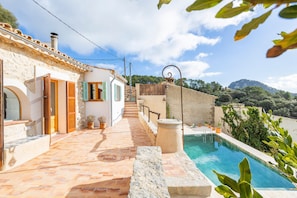 Una villa con piscina, sendero de piedra y vistas del paisaje circundante.