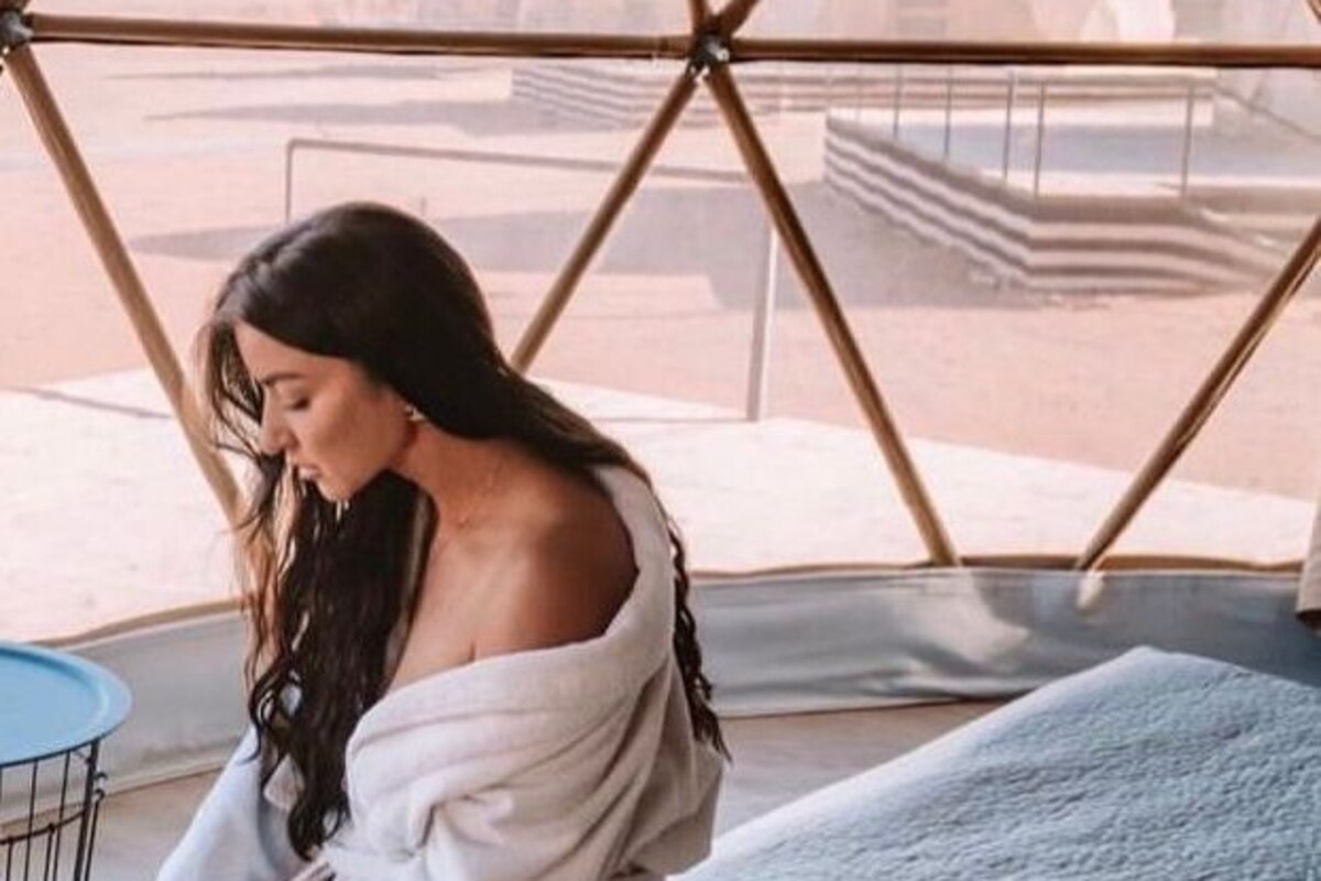 A person sitting on a bed inside a tent with a view of mountains.