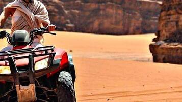 A person riding an ATV in a desert landscape with rocky formations.
