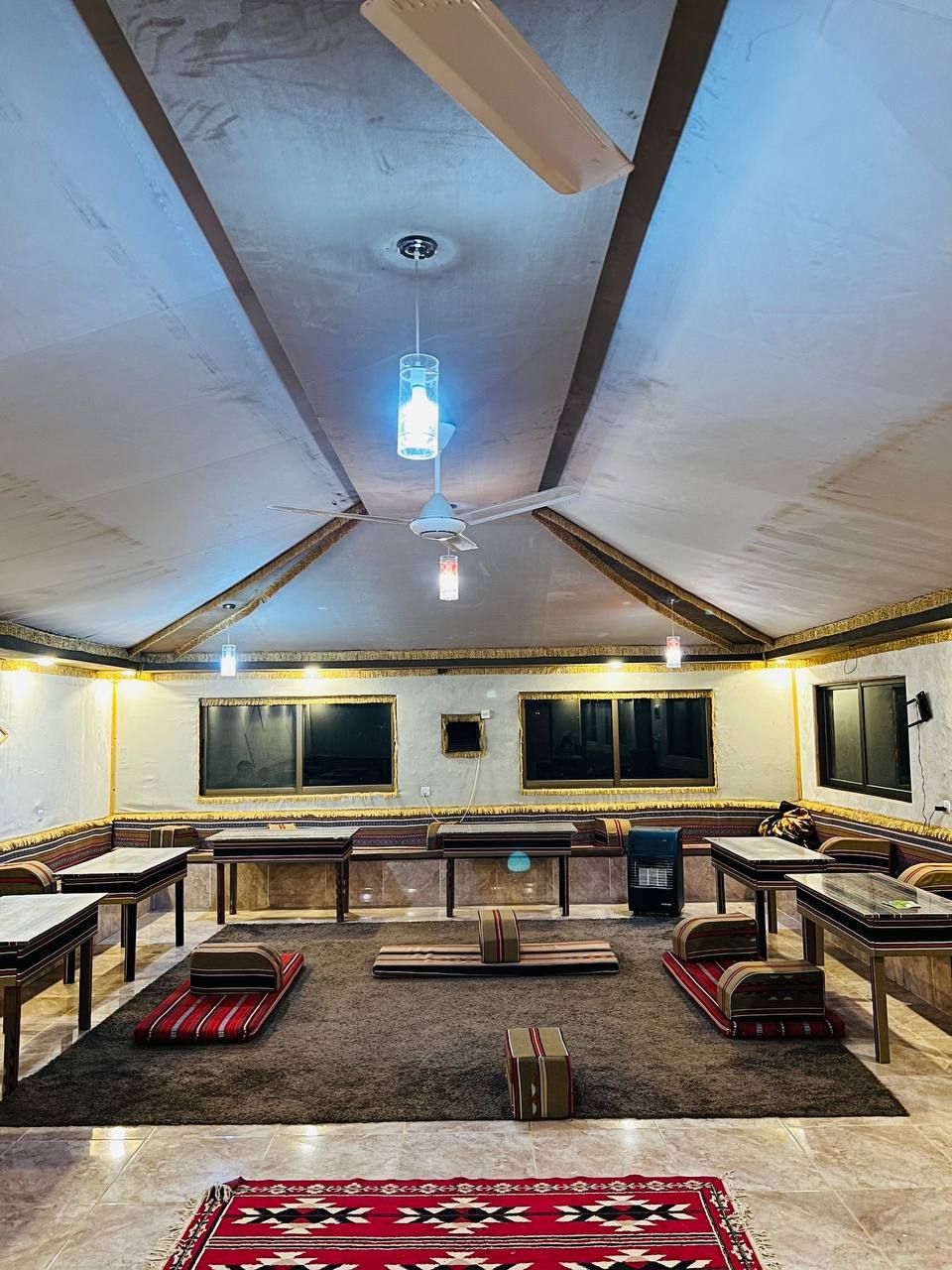 Une pièce spacieuse avec un plafond haut, un ventilateur de plafond et une grande fenêtre.