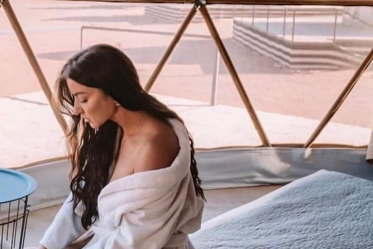 A person sitting on a bed inside a tent with a view of mountains.