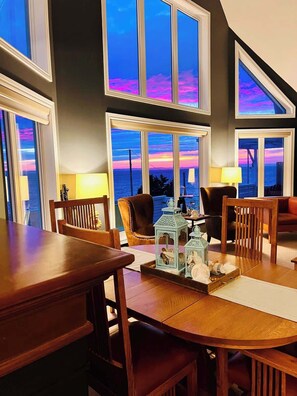 Enjoy expansive ocean views from the room's large windows, featuring a dining table for four and comfortable seating.