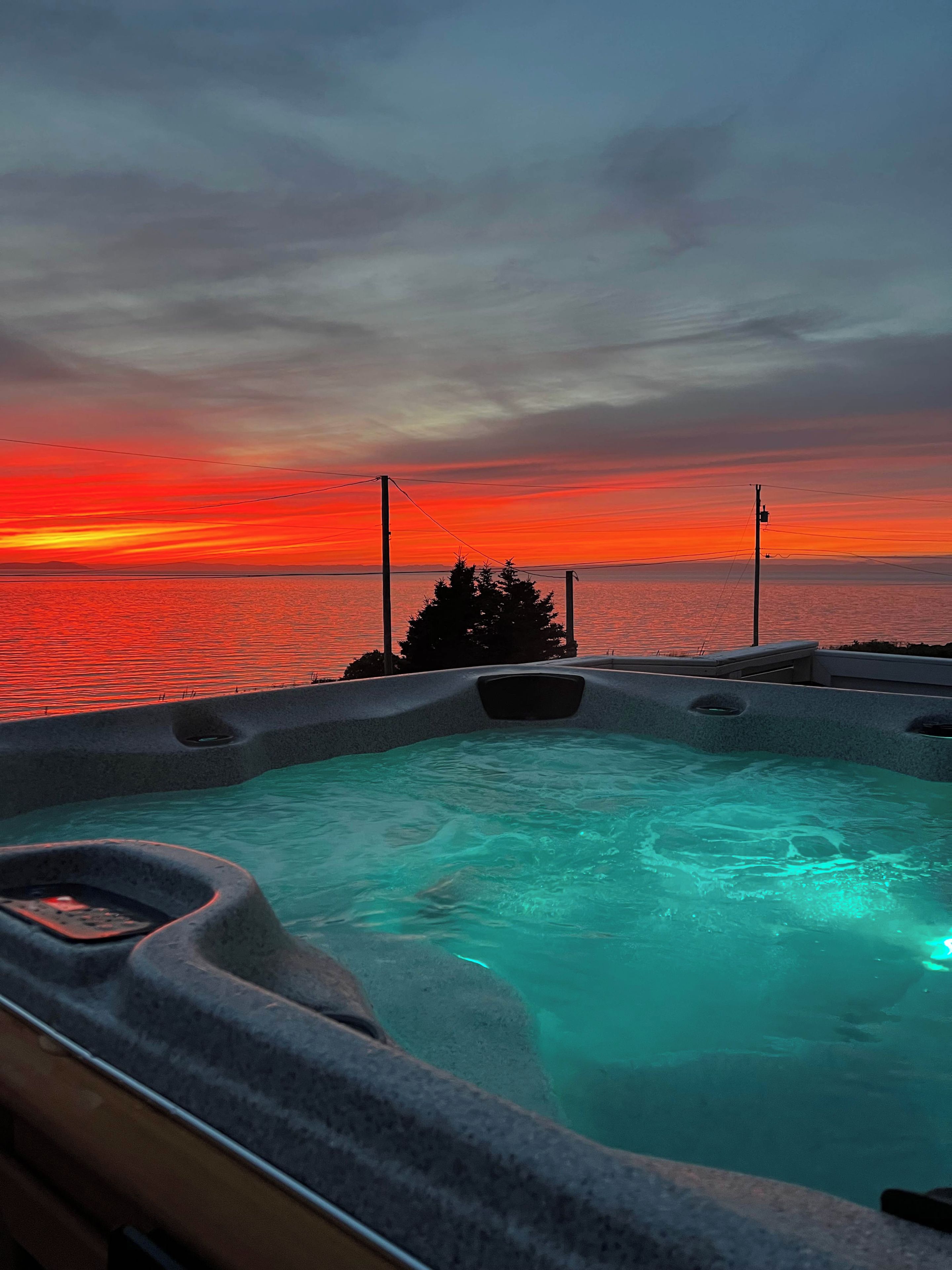 A hot tub with a view of the sunset over the water.
