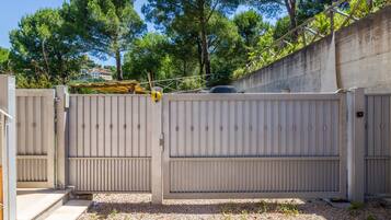 Ein durch eine Mauer und ein Metallgitter geschütztes Gelände, umgeben von Kies und Bäumen.