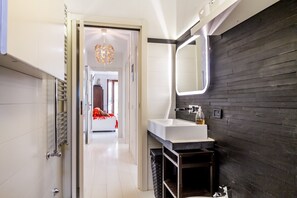 A modern bathroom with a white sink, dark wooden wall, and a mirror.