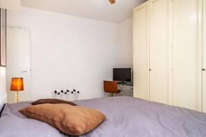 Ein Schlafzimmer mit Bett, Schreibtisch, Stuhl, Fernseher und Kleiderschrank.