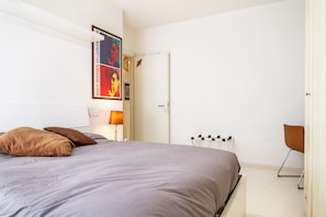 A bedroom with a bed, pillows, a lamp, a radiator, and a door. - Apartment 'Aia Delle Streghe Scarlino Maremma' with Private Terrace, Private Garden and Balcony (Scarlino)