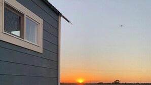 Ein kleines Haus mit Schotterauffahrt und Blick auf den Sonnenuntergang.