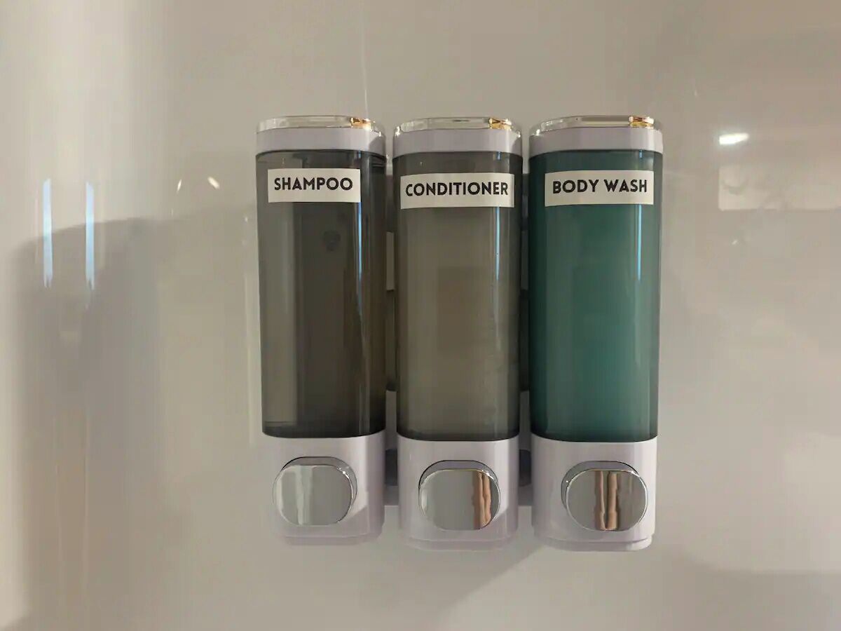 Tre behållare med påskrifterna ”SCHAMPO”, ”BALSAM” och ”DUSCHGEL” monterade på en vägg.