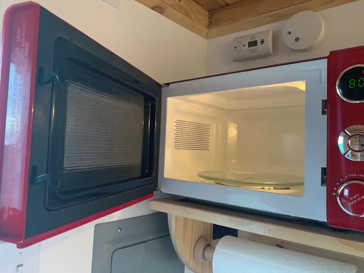 Eine kompakte Mikrowelle mit digitalem Display, Bedienfeld und einem Gittergitter.