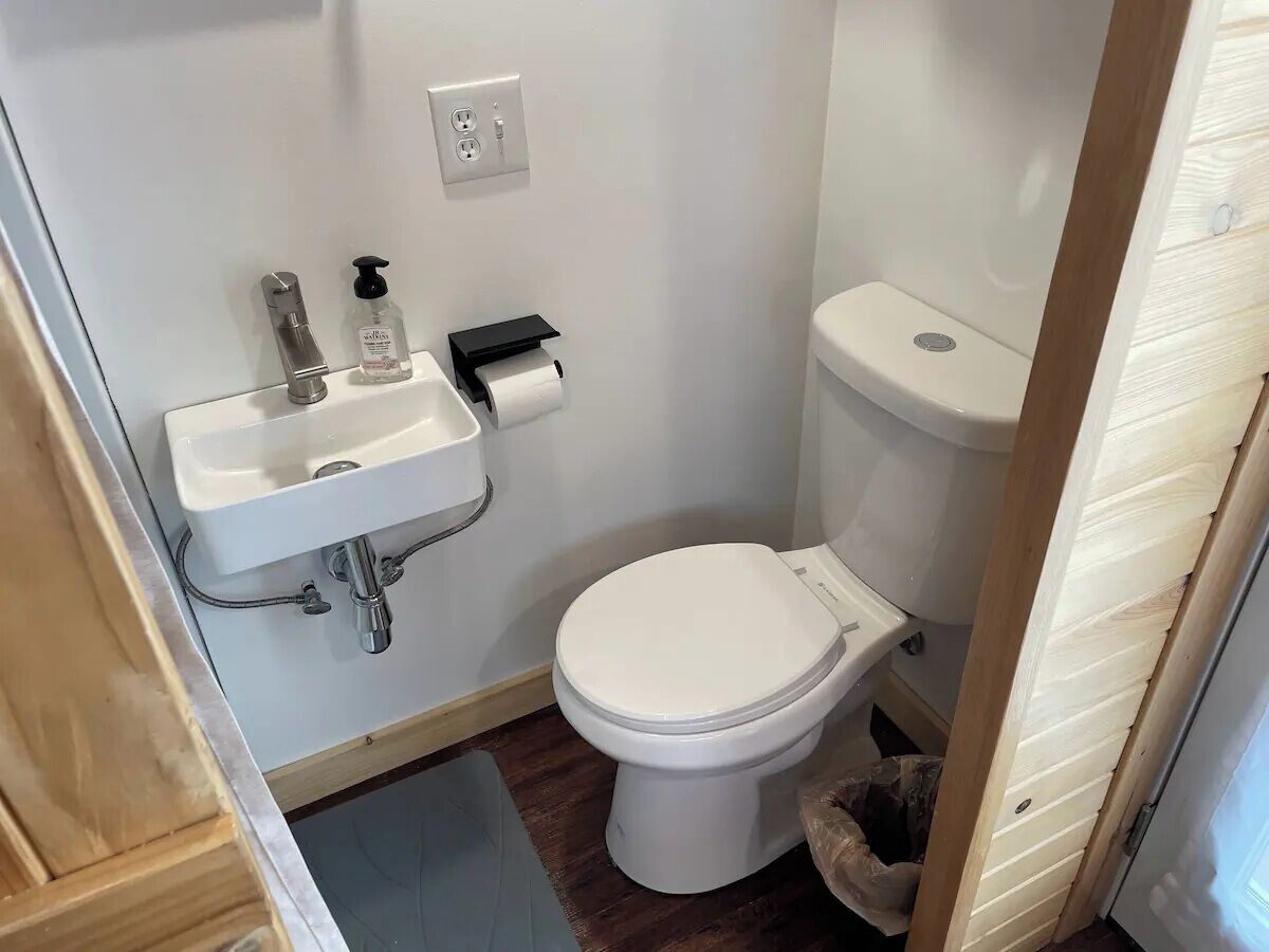 Un baño pequeño con un lavamanos blanco, un inodoro y un cubo de basura.