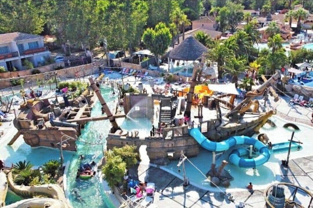 A water park with multiple slides and pools, surrounded by palm trees and buildings.