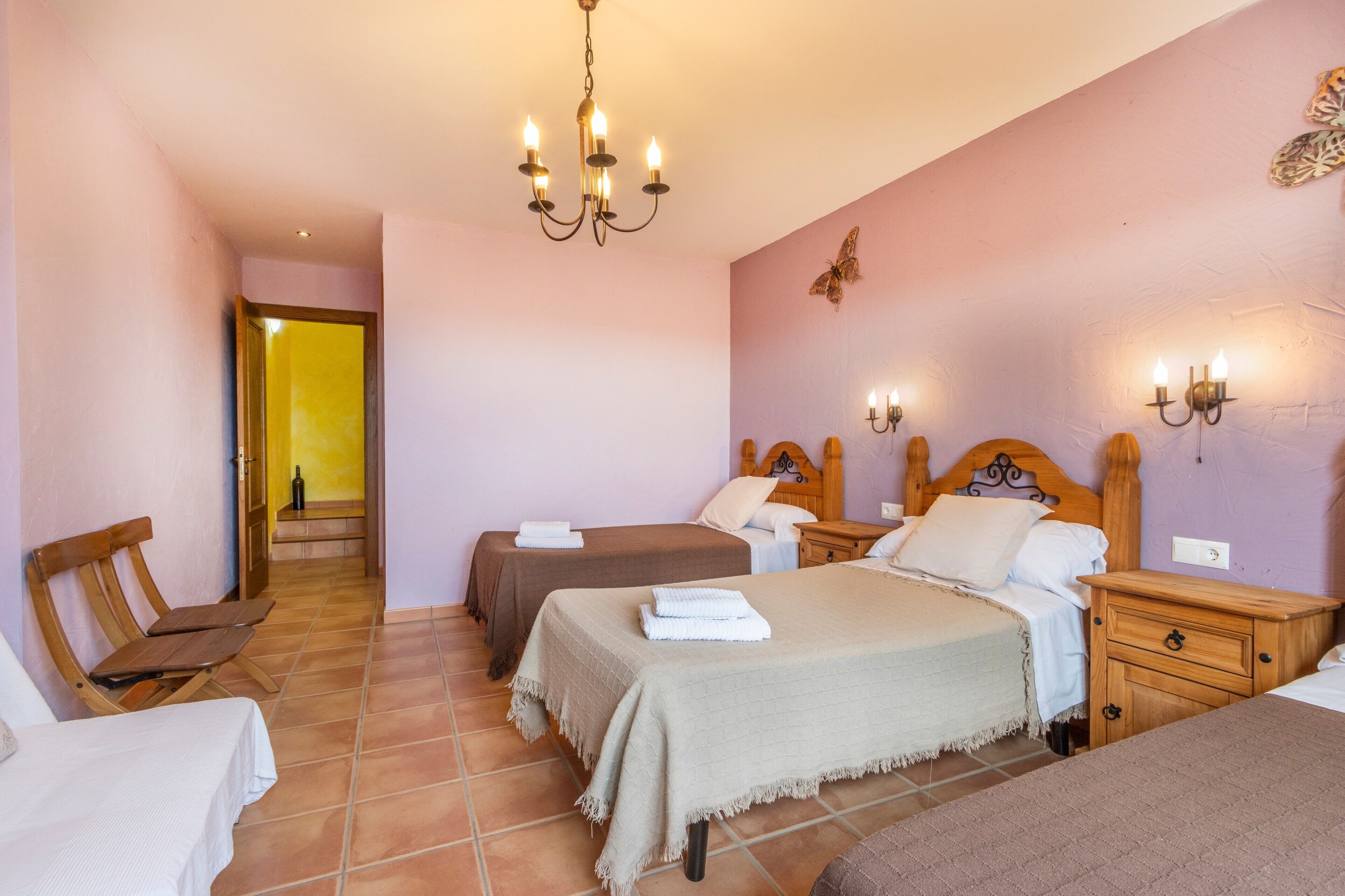 Ein Schlafzimmer mit zwei Betten, einem Holznachttisch, einem Sessel und einer Pendelleuchte.
