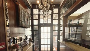 A narrow hallway with a chandelier, a fire extinguisher, and a door with windows. - The Marker Hotel (London)