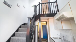A staircase with a wooden railing leading to a landing, a skylight above, and a kitchen area with a sink and cabinets. - Host Stay St Martin s Road (Canterbury)
