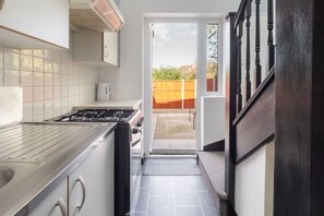 A kitchen with a gas stove, white cabinets, and a view of the backyard through an open door. - Host Stay St Martin s Road (Canterbury)