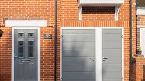 A brick building with two grey doors, one with a window and a sign above it. - Host Stay St Martin s Road (Canterbury)