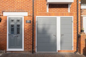 A brick building with two grey doors, one with a window and a sign above it. - Host Stay St Martin s Road (Canterbury)