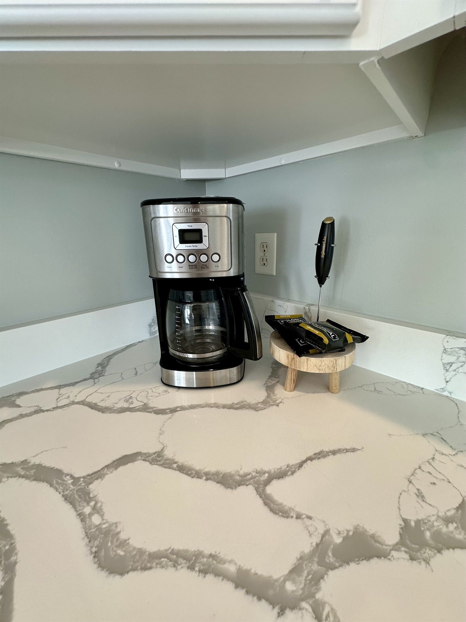 Een keuken met een koffiezetapparaat, een messenblok en een marmeren aanrecht.