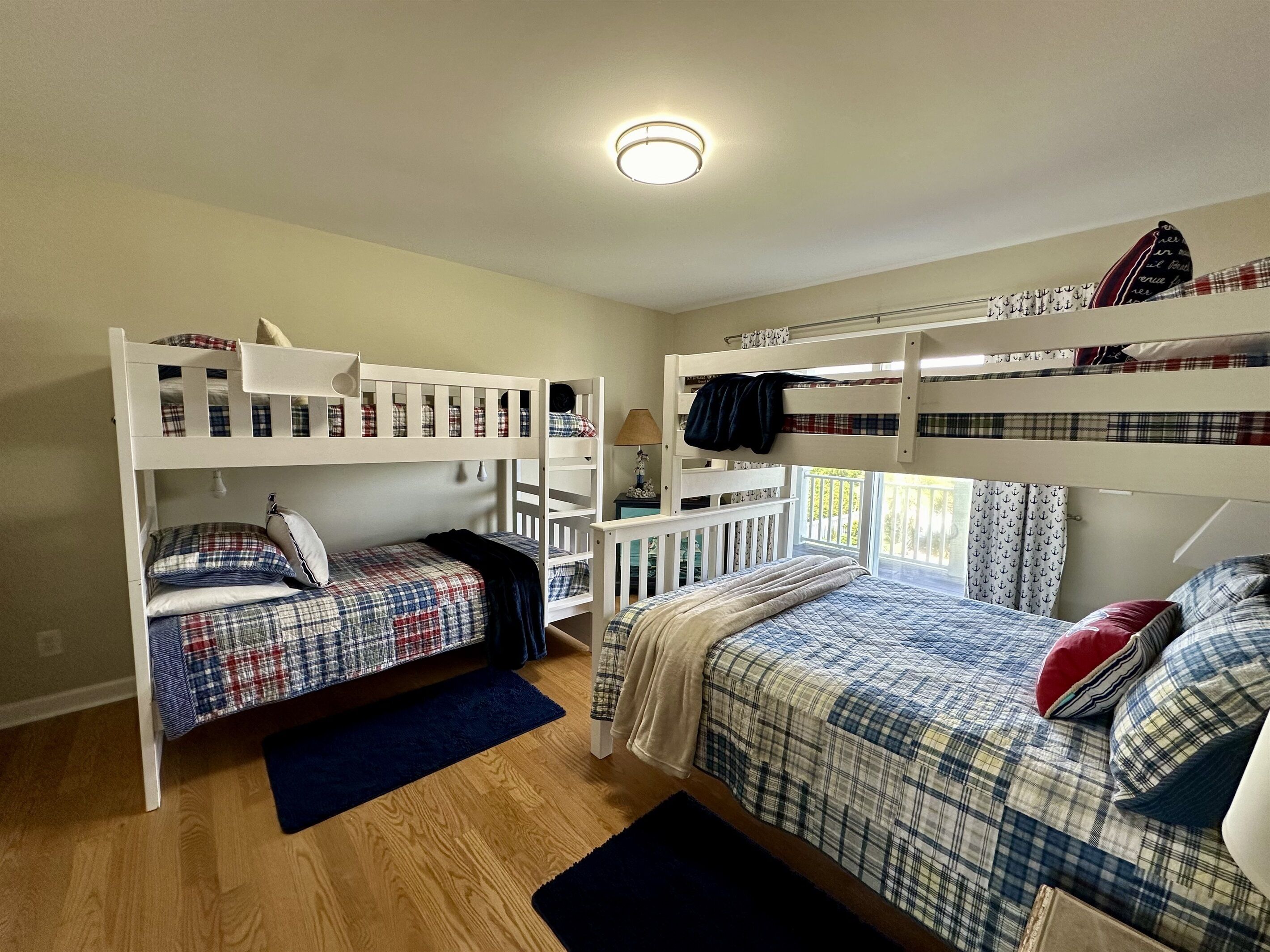 Een kamer met twee stapelbedden, een bureau en een raam met gordijnen.