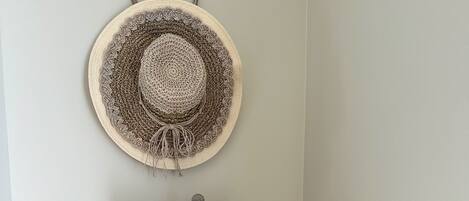 A corner with a lamp, a woven basket with books, and a wall-mounted hat.