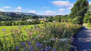 A rural landscape with a road, fields, and houses in the distance. - 1 bedroom accommodation in Slaidburn (Slaidburn)