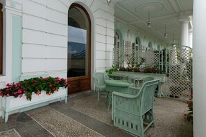 A covered outdoor seating area with wicker furniture, a bench with flowers, and a decorative lattice. - Studio Apartment 'Au Temps Suspendu' with Mountain View, Balcony and Wi-Fi (Aix les Bains)