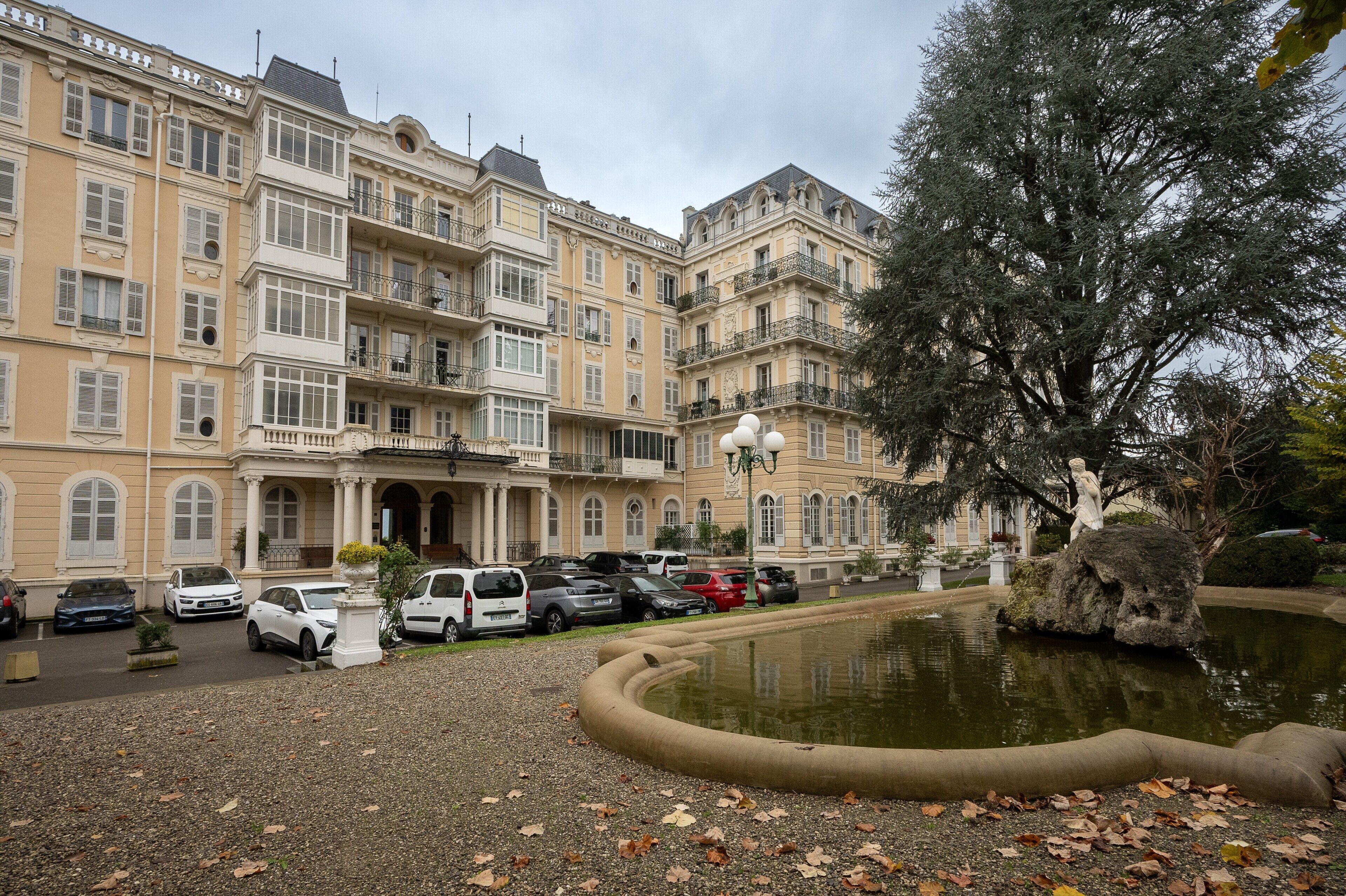 Un hôtel à plusieurs étages doté d’une cour intérieure, d’un parking et d’une statue.