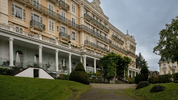 A multi-story hotel with a grand facade, columns, and balconies.