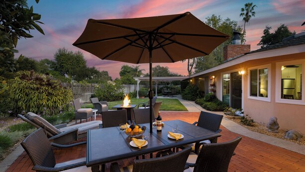 Une terrasse extérieure avec une table, des chaises et un grand parasol.