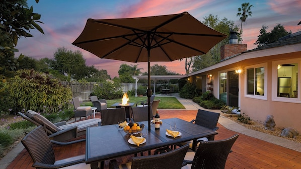 An outdoor patio with a table, chairs, and a large umbrella.