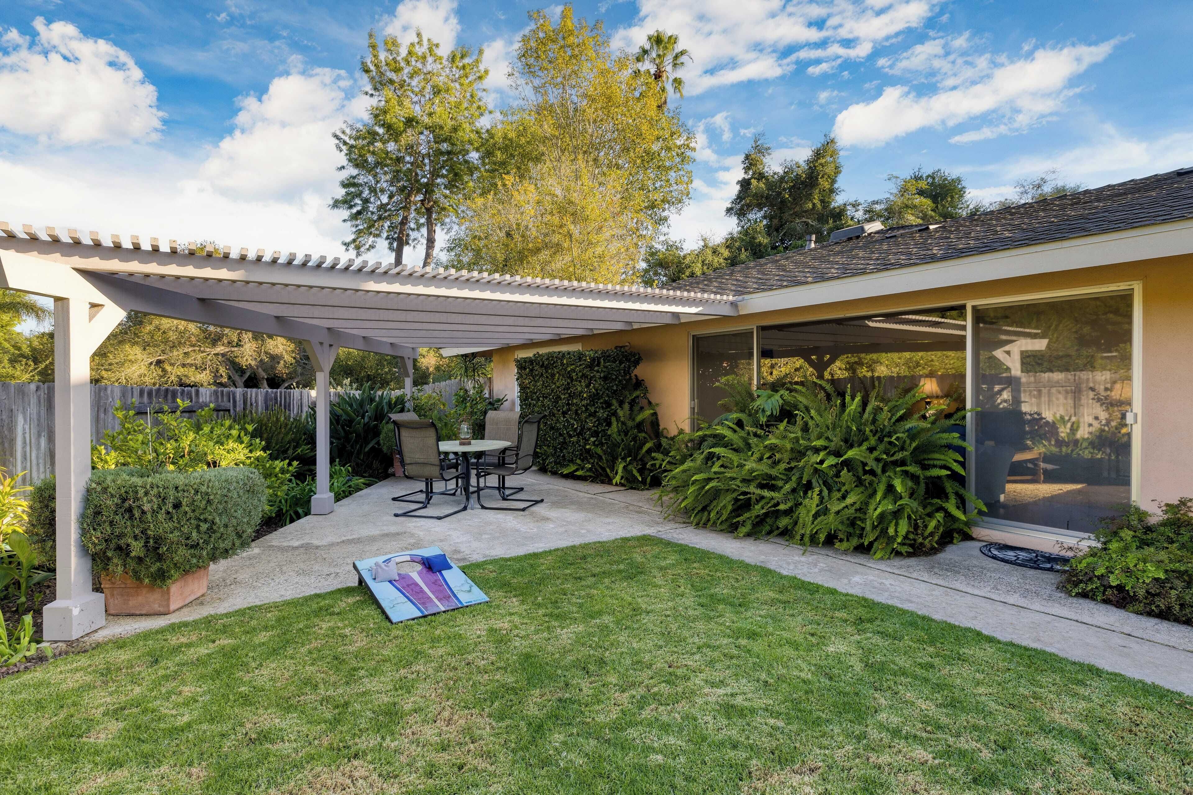 A patio with a covered seating area, a lawn, and a garden.