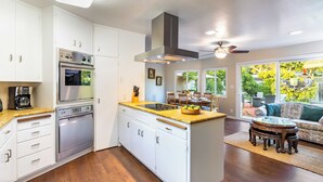 Une cuisine moderne avec des meubles blancs, des appareils en acier inoxydable et un  îlot central.