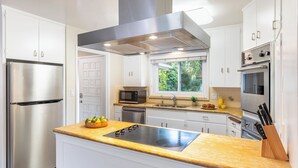 Une cuisine moderne dotée d’appareils électroménagers en acier inoxydable, d’un four encastré et d’une fenêtre donnant sur un paysage verdoyant.