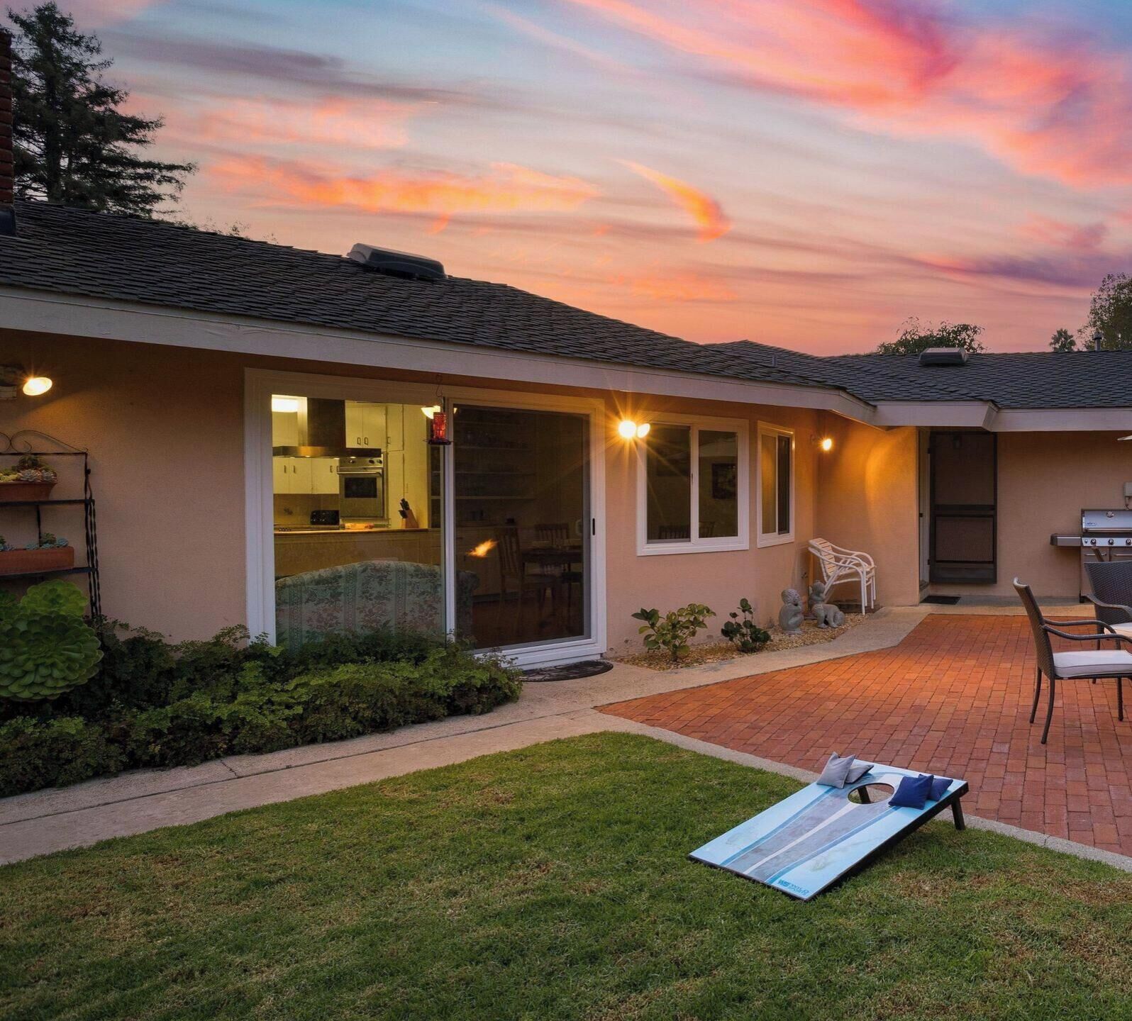 Una casa con un patio, una parrilla y un jardín.