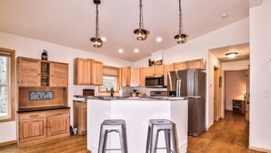 A modern kitchen with wooden cabinets, stainless steel appliances, and a central island with stools. - Long Lake Escape Three Lakes (Eagle River)