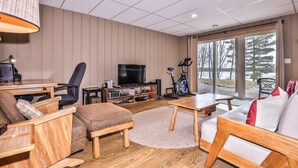 A modern living room with a TV, seating, and a view of the outdoors. - Long Lake Escape Three Lakes (Eagle River)