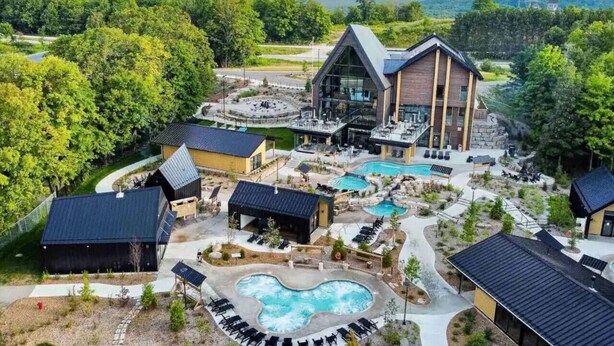 Ein Resort mit einem großen Gebäude, mehreren Pools und Sitzbereichen im Freien, umgeben von Bäumen.