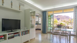 Un soggiorno moderno con una TV a schermo piatto, una libreria e un'area pranzo con sedie e tavolo.