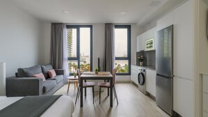 Un apartamento moderno con comedor, kitchenette y un ventanal con vistas a la ciudad.