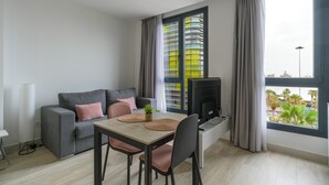 Una sala de estar moderna con un sofá gris, una mesa de comedor de madera y un televisor.