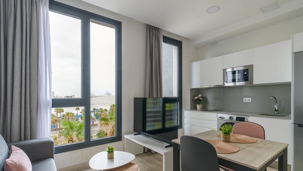 Un apartamento moderno con comedor, cocina y un amplio ventanal con vistas a la ciudad.